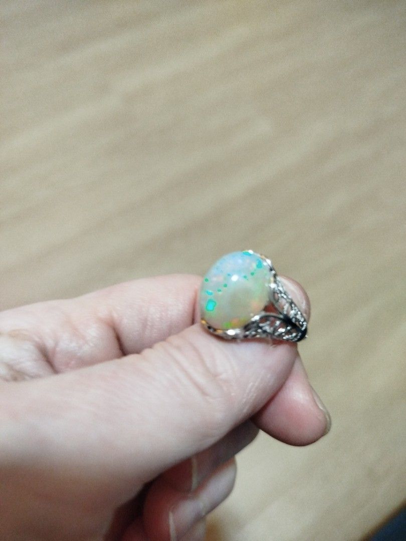 Opal ring (Category: Rings) located in Singapore. Submitted by subaru2.0 (Listing ID 1453523924, Image 2). Description: - Features a captivating large opal with a vibrant play of colors (green, blue, orange hints). - Elegant and detailed metal setting. - Ideal for adding a unique touch to any outfit. Very suitable for occasional time with a statement for conversation..