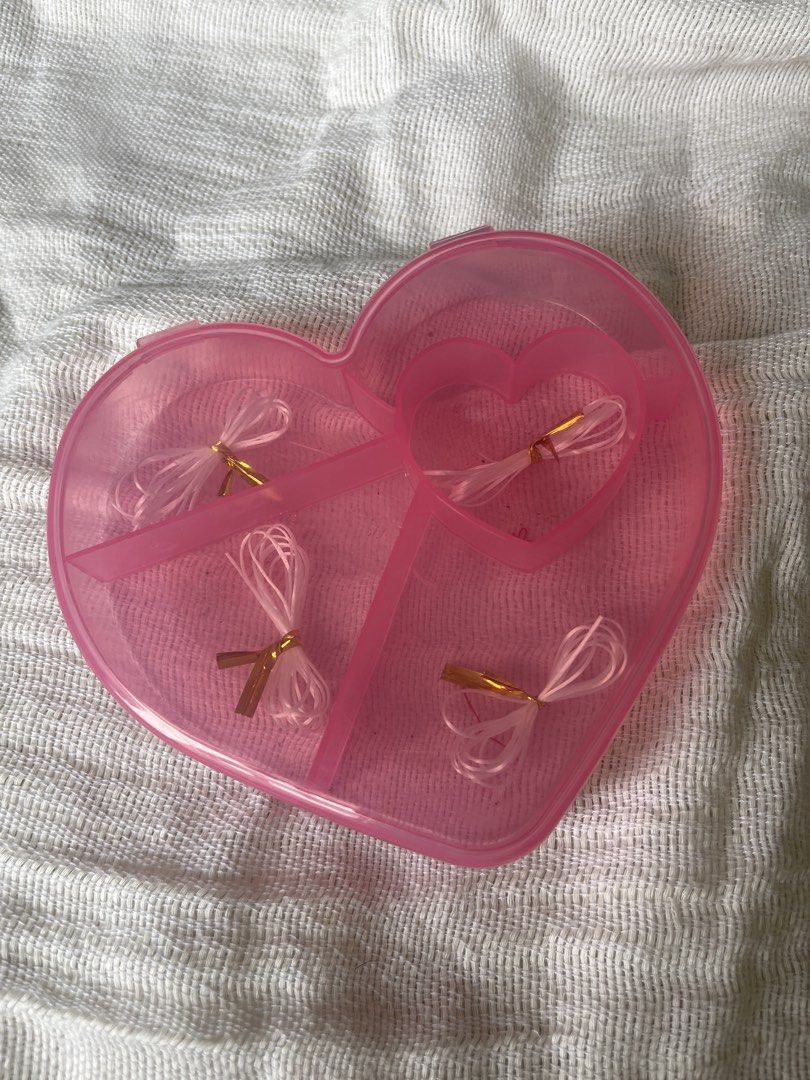 Pink Heart Container with Beading Thread (CAN ADD BEADS UPON REQUEST) (Category: Hair Accessories) located in Manila. Submitted by prima_onda (Listing ID 1453474827, Image 2). Description: - Adorable pink heart-shaped container - Features four internal compartments - Each compartment contains a white hair tie with a stylish gold accent - Ideal for organizing small accessories like hair ties, jewelry, or pills - Compact and secure, making it perfe