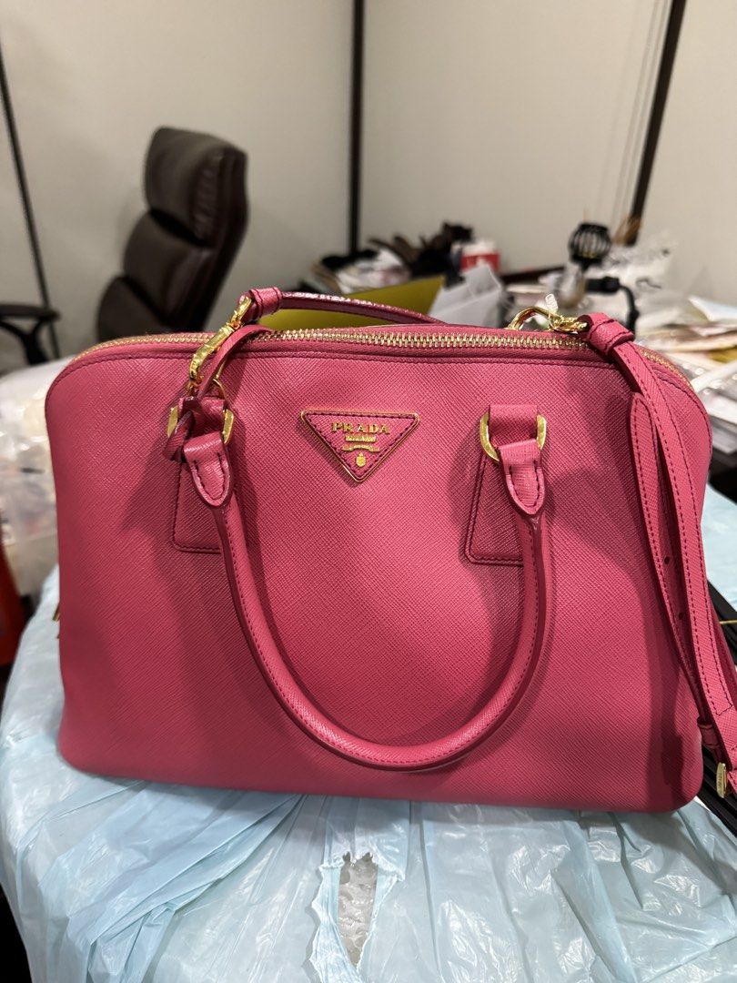 Prada Saffiano Leather Pink Top Handle Bag (Category: Luxury Bags & Wallets) located in Mandaluyong City. Submitted by rdangeles18 (Listing ID 1453517612, Image 1). Description: Prada Promenade Saffiano Leather Bag – Pink Authentic item, purchased in Japan. Included: * Original dust bag Condition: * Minor dent on the front, above the Prada logo * Light hairline scratches on the bottom hardware * Overall still in good condition Price is slightly n