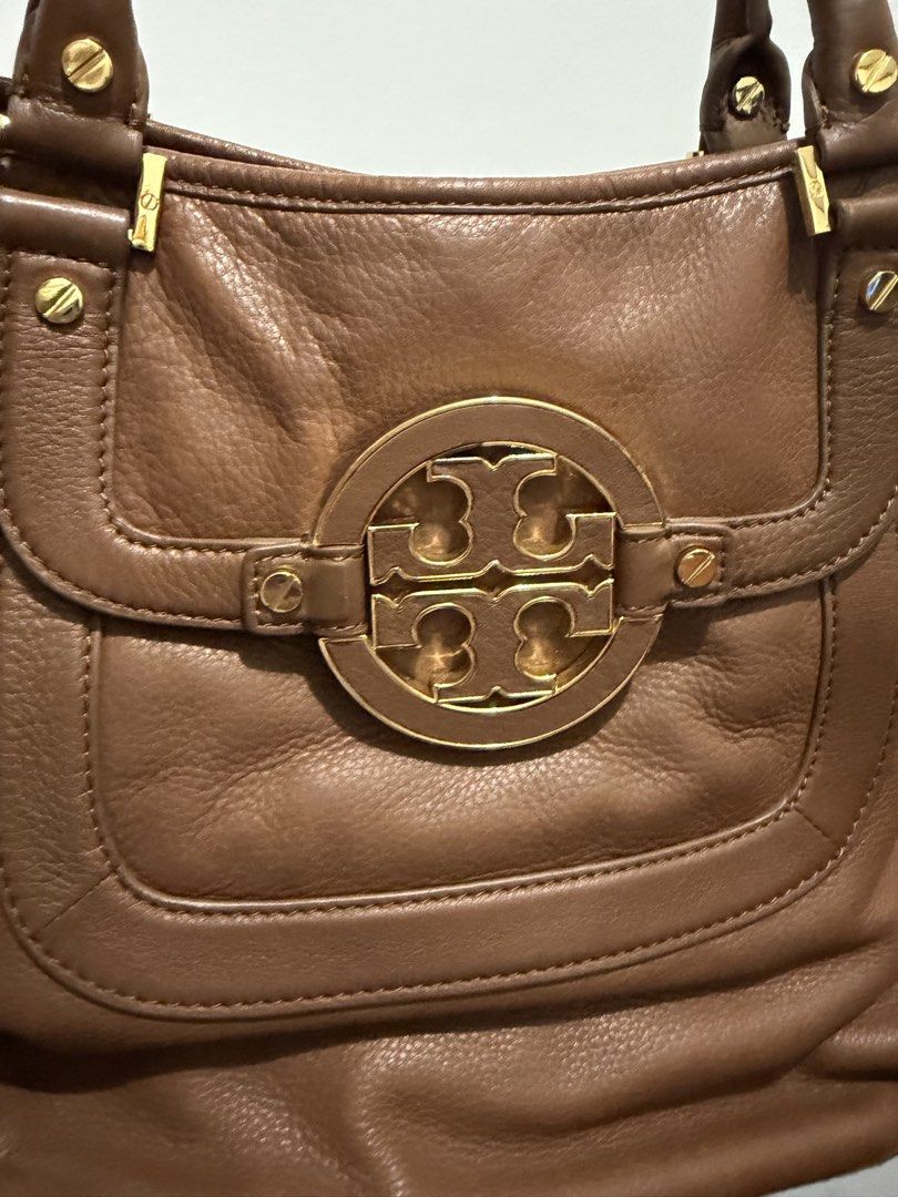 Tory Burch Amanda Hobo 2-way bag (Category: Luxury Bags & Wallets) located in Muntinlupa City. Submitted by bashabells (Listing ID 1453566613, Image 3). Description: - Authentic Tory Burch brown leather tote bag - Features iconic gold logo hardware on the front - Comfortable top handles for easy carrying, original long leather strap is included - Shows minor signs of wear on bottom corners, consistent with use - Flaw on lower left corner due to s