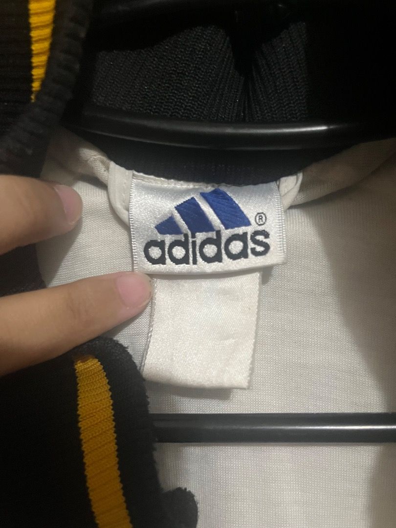 Adidas Track Jacket Black White Yellow Logo (Category: Coats, Jackets and Outerwear) located in Caloocan City. Submitted by riyenrie (Listing ID 1458537914, Image 2). Description: - Classic Adidas track jacket - Black sleeves and collar - White body with yellow Adidas logo on chest - Large Adidas logo graphic on back with yellow and teal accents - Ribbed cuffs and hem with yellow and black stripes - Zip-up front - Perfect for casual wear or sport