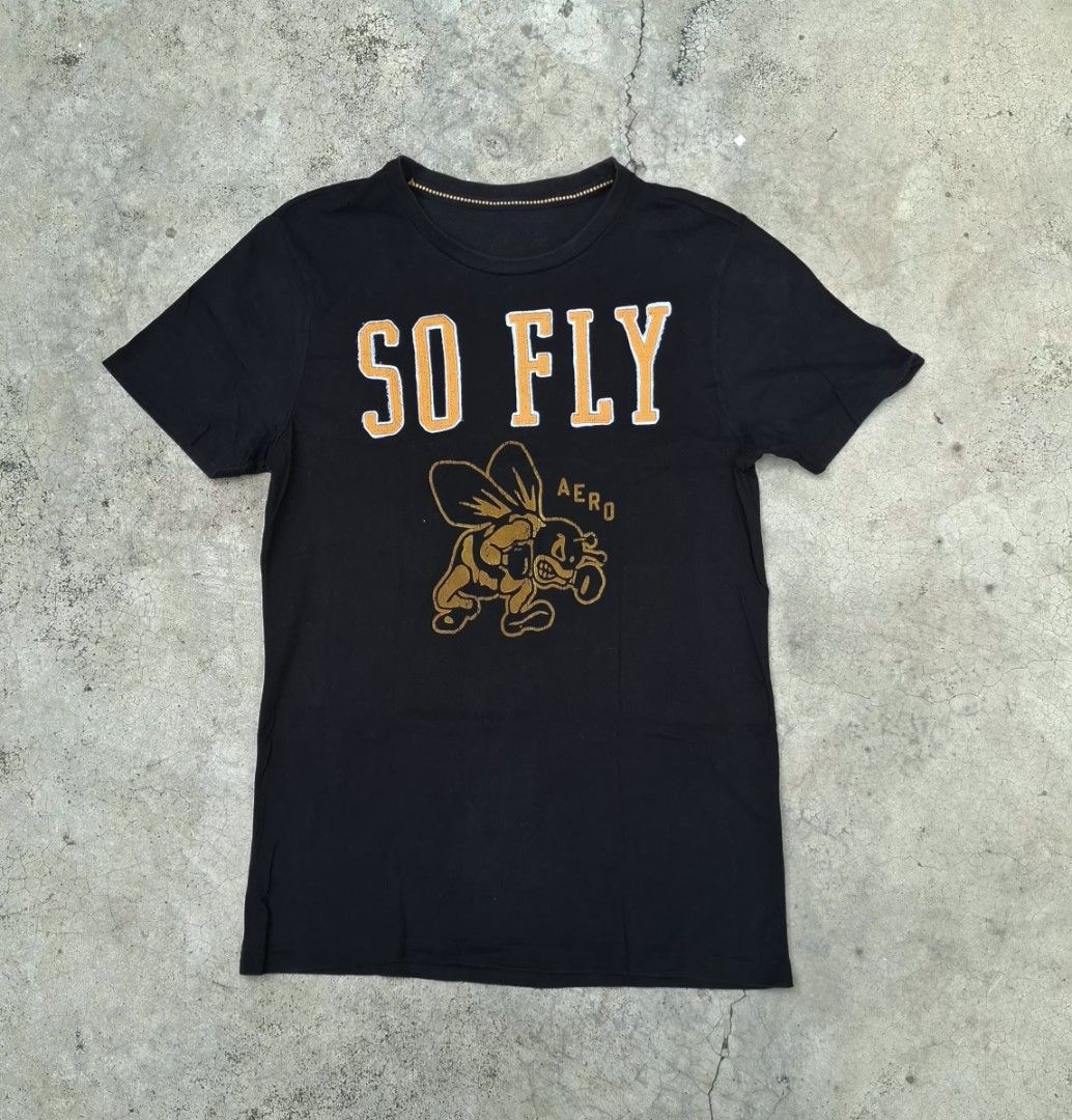 AERO "SO FLY" Bee Graphic T-Shirt (Category: Tshirts & Polo Shirts ) located in Iriga City. Submitted by _the_thrift_store_01 (Listing ID 1458574012, Image 1). Description: - Stylish black t-shirt - Features a "SO FLY" graphic with a bee wearing sunglasses - "AERO" text also included in the graphic - Classic crew neck and short sleeves - Ideal for casual everyday wear.