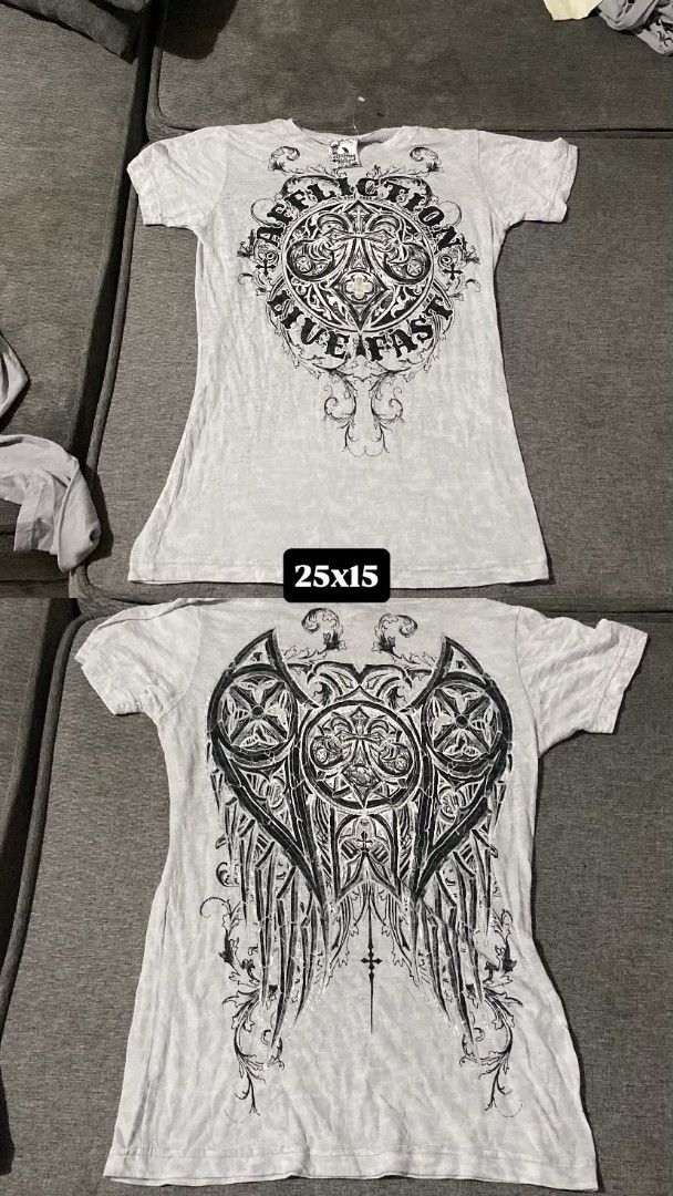 Affliction "Live Fast" Graphic T-Shirt (Category: Tshirts & Polo Shirts ) located in Cagayan de Oro. Submitted by mark.clothing (Listing ID 1458667526, Image 1). Description: - Brand: Affliction - Color: Light Grey with Black Distressed Print - Design: 'Live Fast' graphic on front, large wing design on back - Style: Short sleeves, crew neck - Estimated Size: Medium (Flat lay measurements: 25 inches length x 15 inches width) - Condition: Great for