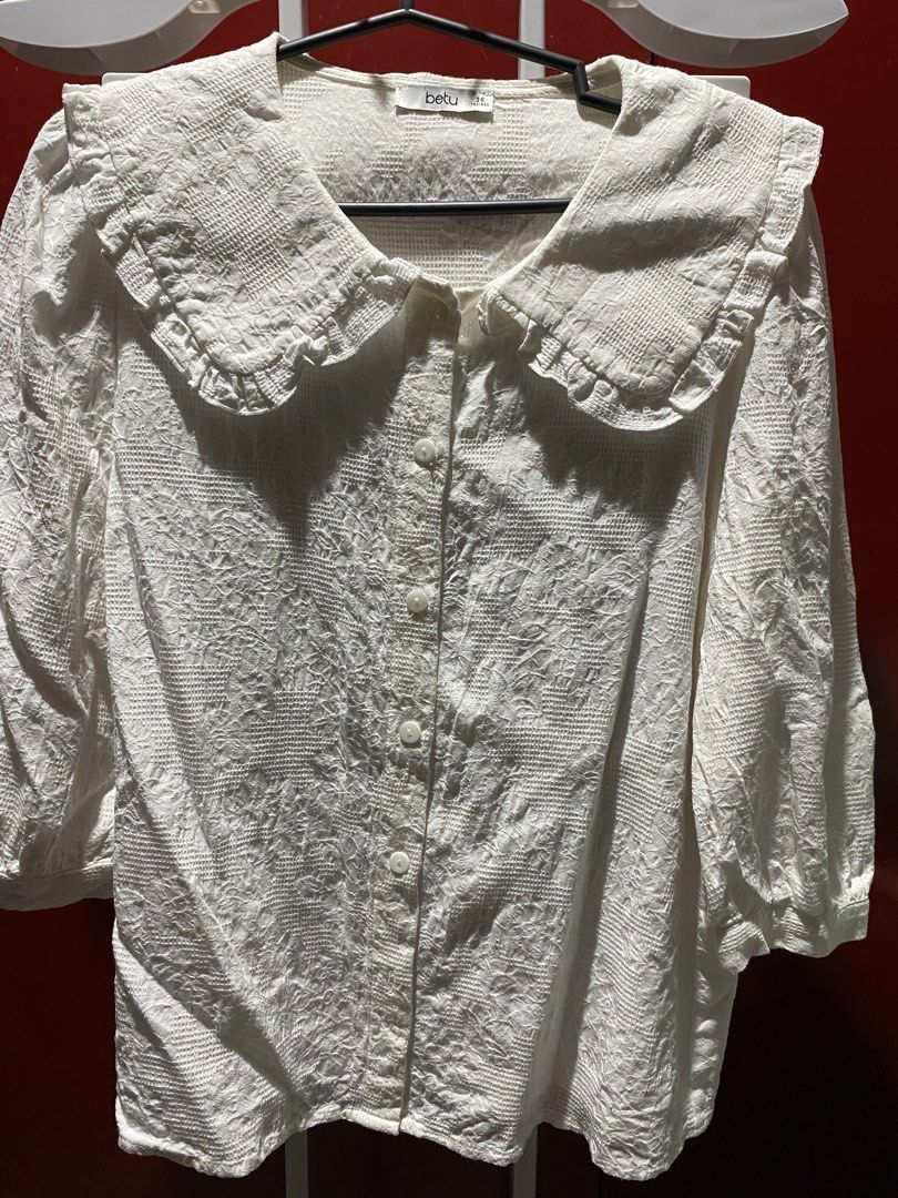 Betu White Textured Peter Pan Collar Blouse (Category: Blouses) located in Bauang. Submitted by nrrandomthings (Listing ID 1458660288, Image 1). Description: - White Betu blouse - Textured fabric all over - Cute Peter Pan collar with ruffled edges - Button-up front - Three-quarter sleeves - Pairs well with skirts or trousers.