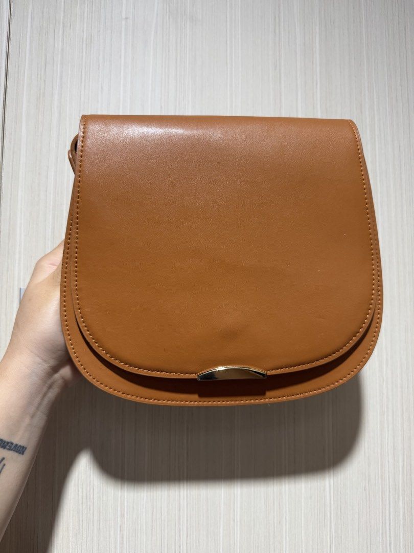 Brown Saddle Bag with Gold Clasp (Category: Luxury Bags & Wallets) located in Bacoor. Submitted by nicafindssince2022 (Listing ID 1458689368, Image 1). Description: - Cute brown saddle bag - Gold clasp closure - Faux leather material - Neat stitching - Minor signs of wear on flap edges (as pictured) - Ideal size for everyday essentials - Great for casual outings - With minimal signs of use.