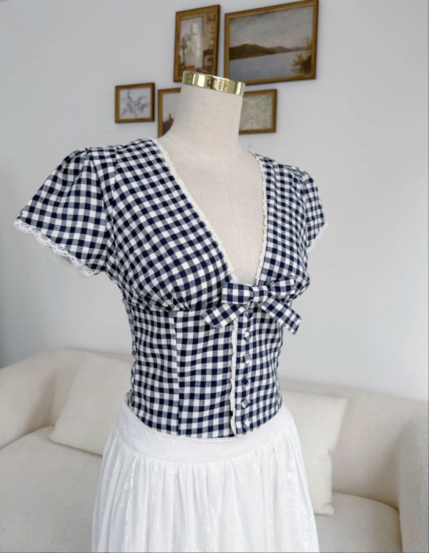Clothes Bar Niori Gingham Top (Category: Blouses) located in Cavite. Submitted by jaimee_go (Listing ID 1458569947, Image 2). Description: The Niori Top – Navy Gingham is a cute and feminine top with a classic navy and white check pattern. With tiny lace details and a sweet bow, this top gives you a youthful and neat look that goes perfectly with high-waisted skirts or pants. Main Fabric: High-quality Linen with a classic navy and white gingham p