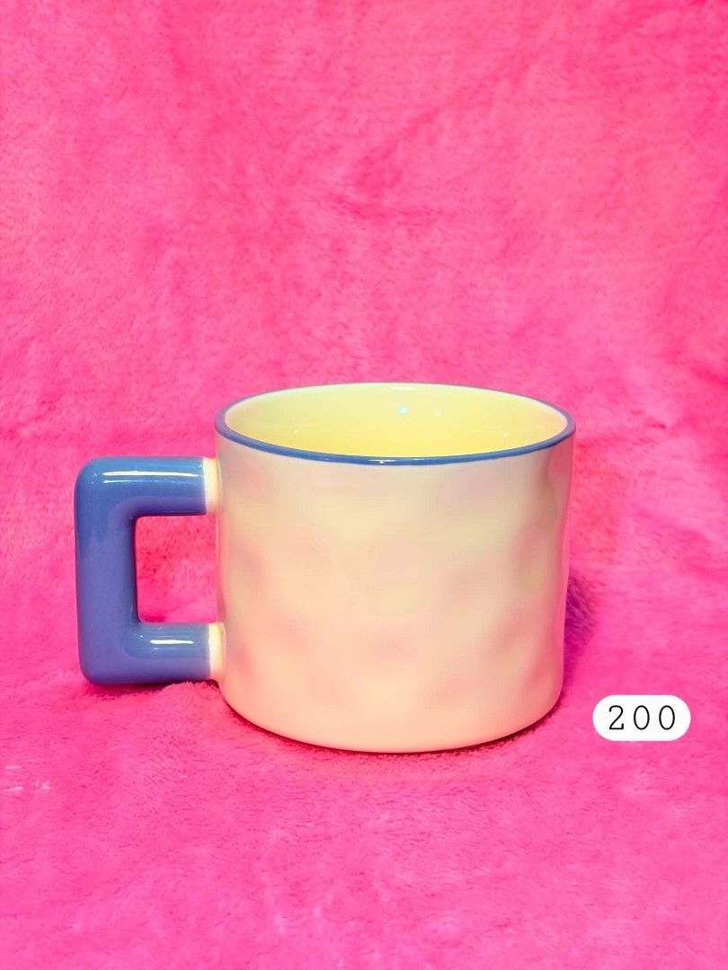 Cute pastel mug with blue handle (Category: Coffee & Tea Tableware) located in Subic. Submitted by swift.thriftz (Listing ID 1458594928, Image 1). Description: - Pastel yellow mug with a textured finish - Bright blue, square-shaped handle - Thin blue line around the rim - Ideal for your morning coffee or tea - Features a unique and eye-catching design.