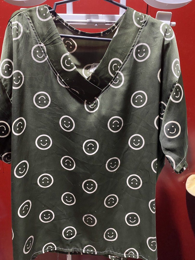 Green Smiley Face V-Neck Top (Category: Shirts) located in Bauang. Submitted by nrrandomthings (Listing ID 1458659717, Image 1). Description: - Adorable green V-neck top - Features a repeating smiley face pattern - Short sleeves for a comfortable fit - Fabric has a subtle sheen - Ideal for casual outfits - Pairs well with jeans or shorts.