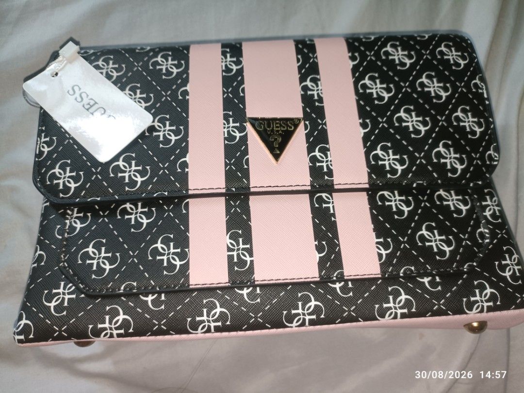 Guess Monogram Clutch Bag with Pink Stripes (Category: Clutches) located in Caloocan City. Submitted by calm.gentle.carleenballes (Listing ID 1458560296, Image 1). Description: - Guess clutch bag with signature monogram print - Features pink stripe details - Gold Guess logo accent - Interior with multiple compartments - Includes a detachable strap - Ideal for evenings out or as a statement piece.