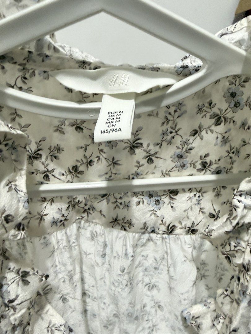 H&M Floral Ruffle Button Up Blouse Size M (Category: Blouses) located in Imus. Submitted by gclmom (Listing ID 1458617540, Image 2). Description: - Delicate white blouse with a charming blue floral print. - Elegant ruffled neckline adds a feminine touch. - Classic button-up front for easy wear. - Three-quarter sleeves with stylish ruffled cuffs. - Made from lightweight fabric, ideal for staying cool. - Effortlessly dress it up or down for any out