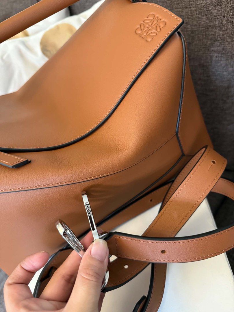 Loewe Puzzle Hobo Bag Tan Leather (Category: Luxury Bags & Wallets) located in Cavite. Submitted by hardt0get (Listing ID 1458635396, Image 2). Description: - Loewe Puzzle Hobo bag - Color: Tan leather - Hardware: Silver - Signature Anagram logo embossed on front flap - Includes detachable shoulder strap - Spacious interior - Ideal for everyday use - medium size.