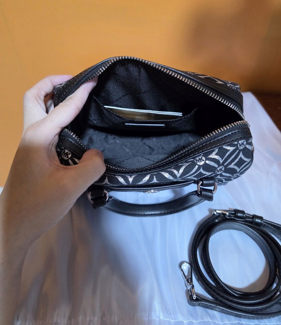 Michael Kors Monogram Mini Duffle Bag (Category: Luxury Bags & Wallets) located in Pasig City. Submitted by miamendoza30 (Listing ID 1458533314, Image 3). Description: - Authentic Michael Kors mini duffle bag - Classic black with signature silver MK monogram pattern - Versatile carrying options: top handles and detachable crossbody strap - Secure zipper closure to keep your belongings safe - Interior slip pocket for small essentials - Ideal size 