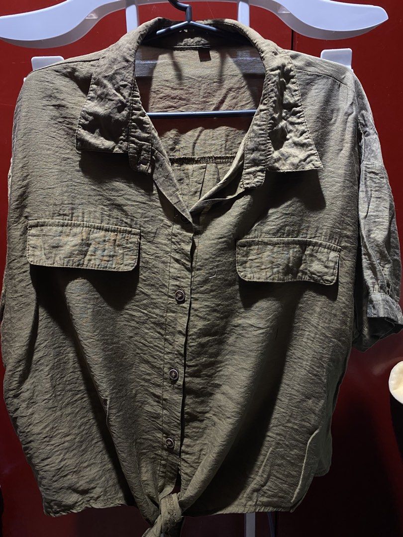 Olive Green Cropped Button-Up Shirt with Tie Front (Category: Shirts) located in Bauang. Submitted by nrrandomthings (Listing ID 1458659087, Image 1). Description: - Olive green short-sleeved shirt - Collared neckline - Button-up front - Two chest pockets - Tie detail at the bottom hem - Crinkled texture material - Relaxed fit.