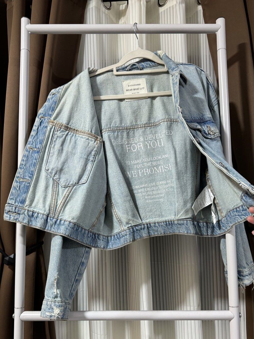 STRADIVARIUS Denim Jacket - Light Wash (Category: Coats, Jackets and Outerwear) located in Makati City. Submitted by prelovedbycj9 (Listing ID 1458676717, Image 3). Description: - Classic light wash denim jacket from Stradivarius - Relaxed fit with button-up front - Features two chest pockets and side pockets - Unique graphic print lining inside - Ideal for easy, casual layering over any outfit.