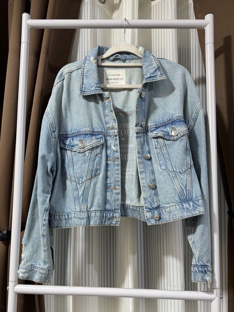 STRADIVARIUS Denim Jacket - Light Wash (Category: Coats, Jackets and Outerwear) located in Makati City. Submitted by prelovedbycj9 (Listing ID 1458676717, Image 1). Description: - Classic light wash denim jacket from Stradivarius - Relaxed fit with button-up front - Features two chest pockets and side pockets - Unique graphic print lining inside - Ideal for easy, casual layering over any outfit.