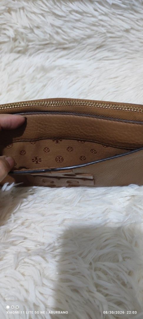 Tory Burch Wallet (Category: Luxury Bags & Wallets) located in Makati City. Submitted by yerbua103 (Listing ID 1458645487, Image 2). Description: This TB features a brown leather zip-around pocket accented with a large embossed double T- logo on the front and a wide slip open compartment. Interior is lined with a monogram, card, coin and bills compartment. Maange your expectations as you're buying a preloved wallet .