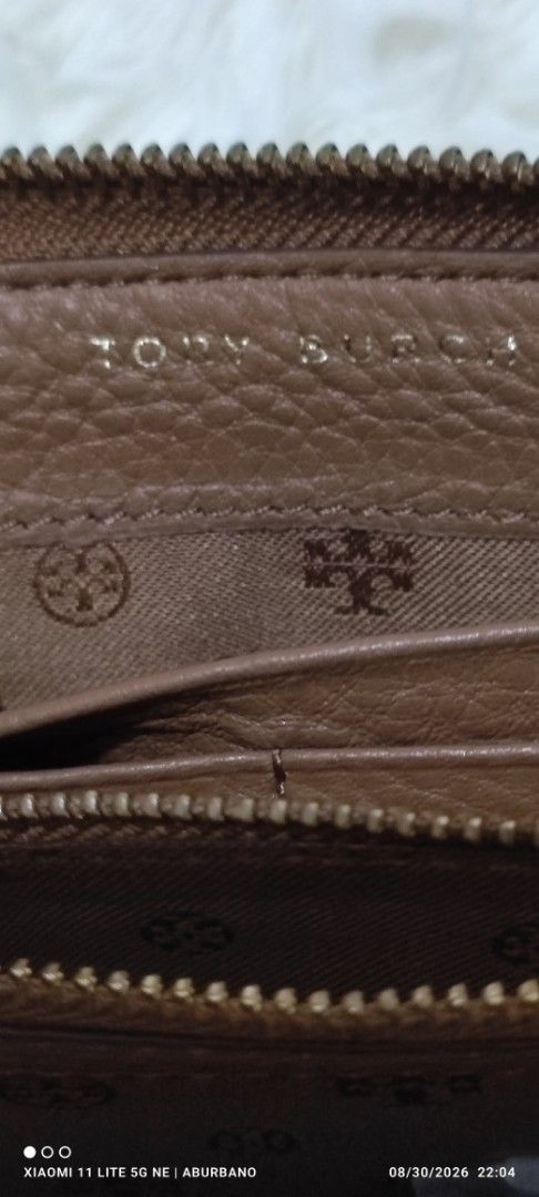 Tory Burch Wallet (Category: Luxury Bags & Wallets) located in Makati City. Submitted by yerbua103 (Listing ID 1458645487, Image 3). Description: This TB features a brown leather zip-around pocket accented with a large embossed double T- logo on the front and a wide slip open compartment. Interior is lined with a monogram, card, coin and bills compartment. Maange your expectations as you're buying a preloved wallet .