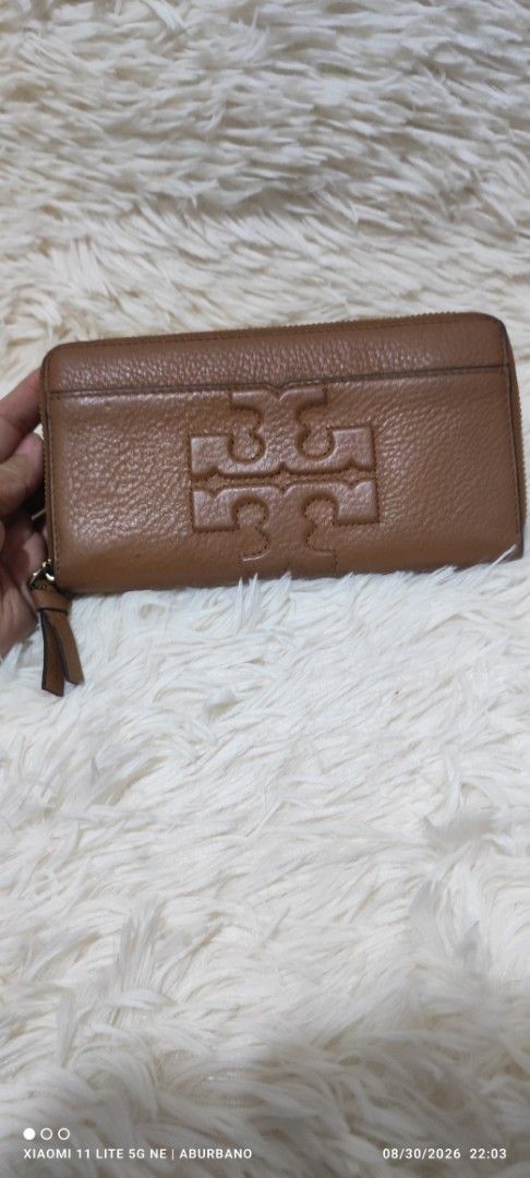 Tory Burch Wallet (Category: Luxury Bags & Wallets) located in Makati City. Submitted by yerbua103 (Listing ID 1458645487, Image 1). Description: This TB features a brown leather zip-around pocket accented with a large embossed double T- logo on the front and a wide slip open compartment. Interior is lined with a monogram, card, coin and bills compartment. Maange your expectations as you're buying a preloved wallet .