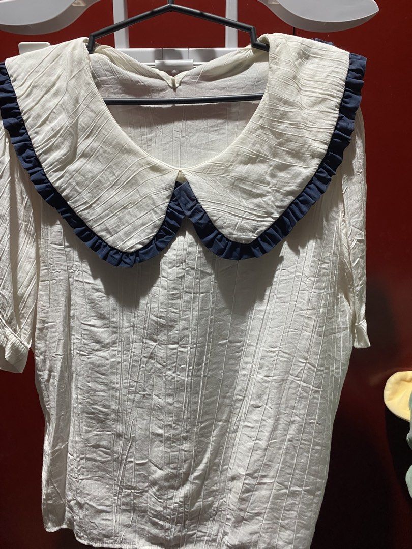 White Blouse with Peter Pan Collar and Navy Trim (Category: Blouses) located in Bauang. Submitted by nrrandomthings (Listing ID 1458660033, Image 1). Description: - White textured blouse - Features a large Peter Pan collar - Navy blue ruffled trim on collar - Short sleeves - Comfortable and stylish - Versatile for casual or semi-formal occasions.