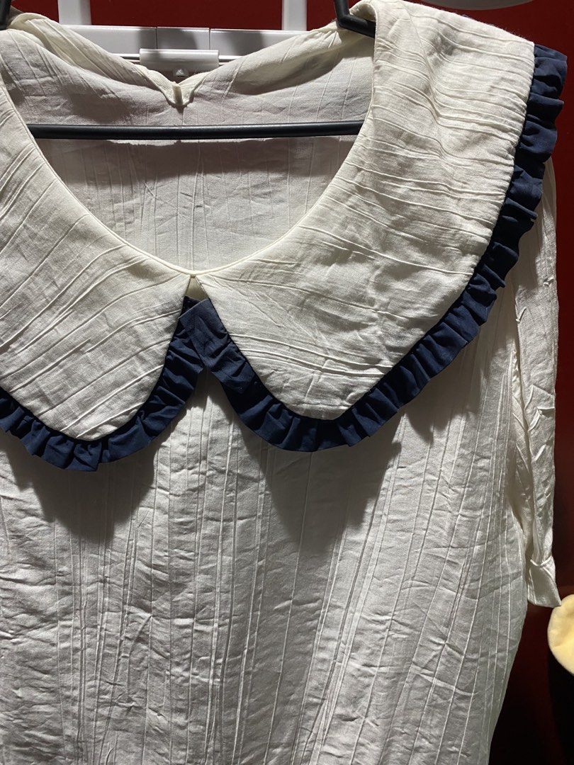 White Blouse with Peter Pan Collar and Navy Trim (Category: Blouses) located in Bauang. Submitted by nrrandomthings (Listing ID 1458660033, Image 2). Description: - White textured blouse - Features a large Peter Pan collar - Navy blue ruffled trim on collar - Short sleeves - Comfortable and stylish - Versatile for casual or semi-formal occasions.
