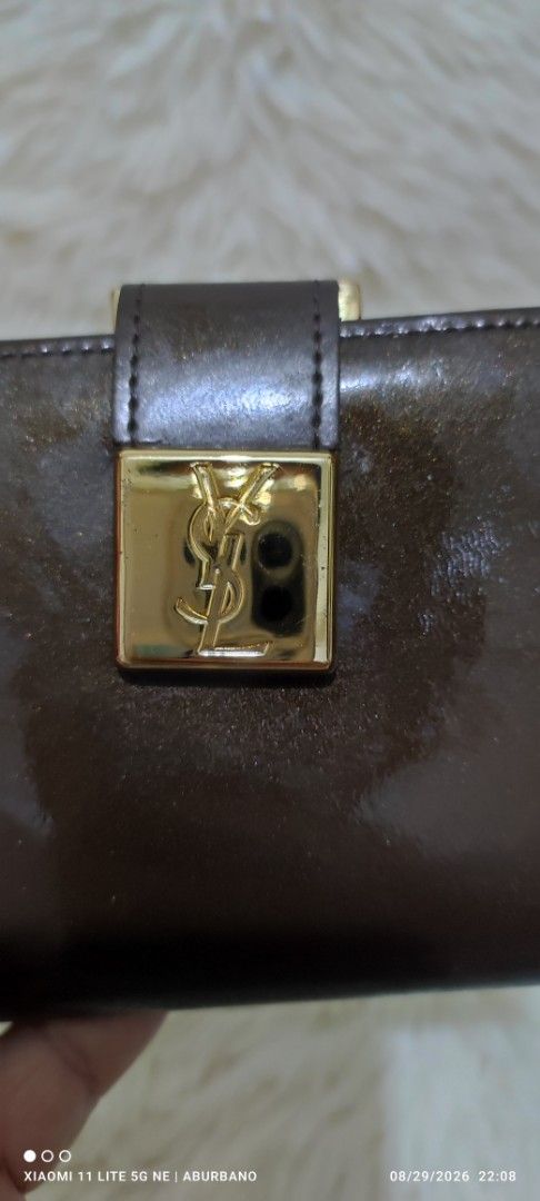 🇯🇵YSL wallet (Category: Luxury Bags & Wallets) located in Makati City. Submitted by yerbua103 (Listing ID 1458594464, Image 1). Description: Vintage Yves Saint Laurent featuring a gold-tone YSL square plaque closure in dark brown patent leather. an ajioka stud or stamp inside a vintage YSL indicates that the item was manufactured in Japan under official licensed agreement by AJIOKA Co. Ltd. Since these pieces were produced locally by AJIOKA mas