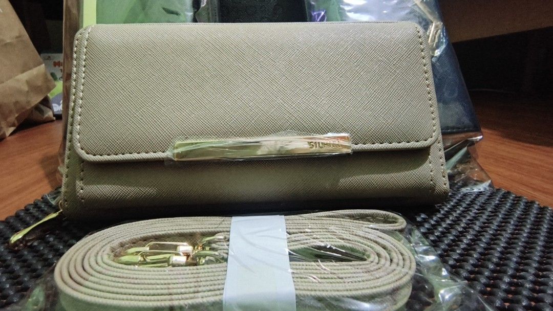 SILFIEL Beige Wallet with Gold Accent and Strap (Category: Luxury Bags & Wallets) located in Manila. Submitted by akosijapok (Listing ID 1458732541, Image 2). Description: SILFIEL 2-Way Crossbody Wallet & Smartphone Bag. It features a beige saffiano-style faux leather finish, a front flap pocket with a gold-tone accent bar, a zip-around main compartment, and a matching detachable shoulder strap. - Stylish beige wallet clutch - Secure zip-around c