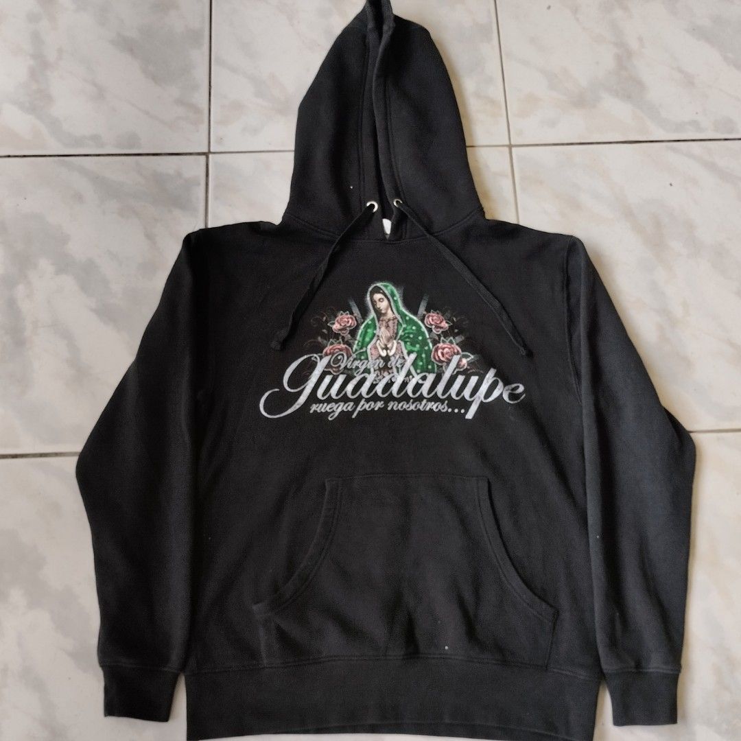 Black Virgen de Guadalupe Hoodie (Category: Hoodies) located in Tagaytay City. Submitted by santino_rio (Listing ID 1458778849, Image 2). Description: - Classic black hoodie - Large, detailed Virgen de Guadalupe graphic on back - Smaller graphic on front - Graphic features roses and praying hands - Comfortable kangaroo pocket - Adjustable drawstring hood - Perfect for fans of this unique style - 22x28 dimes.