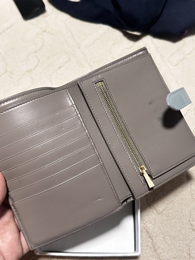 Auth Celine Bi-Fold Wallet (Category: Luxury Bags & Wallets) located in Makati City. Submitted by travel.pasabuy (Listing ID 1458761346, Image 3). Description: - Authentic Celine medium bi-fold - Color: Grey - Material: Textured leather exterior - Closure: Light blue snap closure - Interior: Multiple card slots and a zippered coin pocket - Origin: Made in Italy - Includes: Original box -issue: dirt and pressmark, light crack manageable. Rfs- bawa