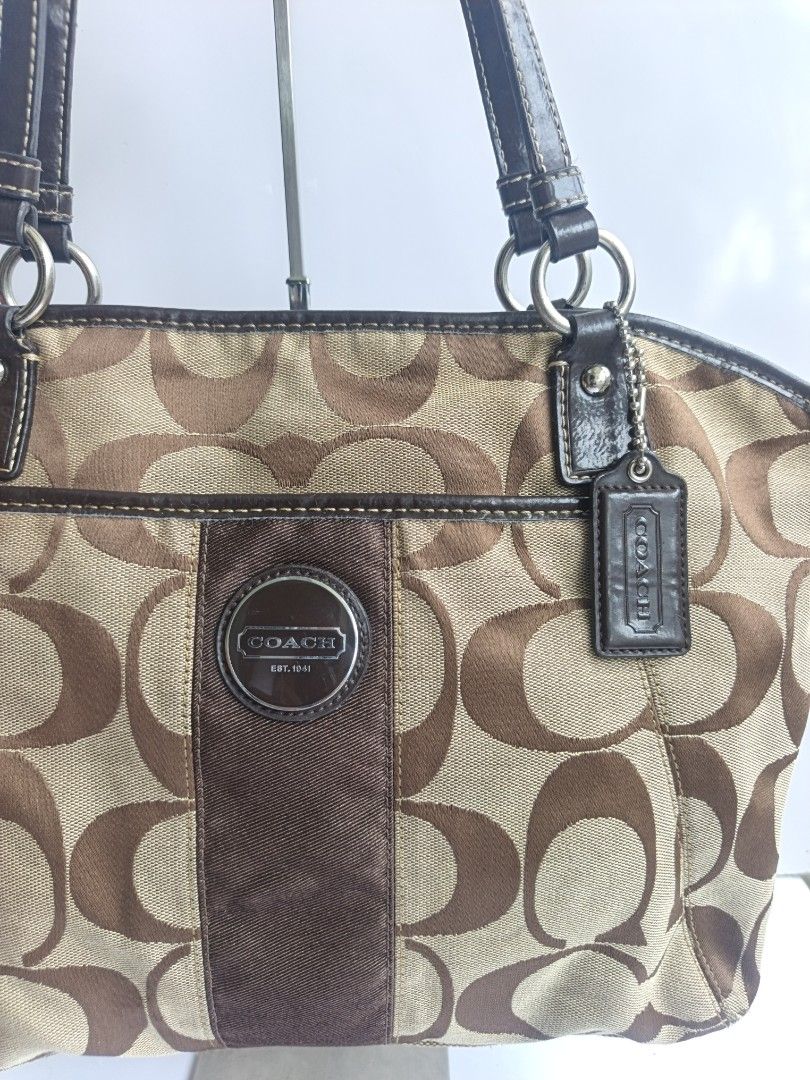 Coach Monogram Canvas Leather Trim Shoulder Bag (Category: Luxury Bags & Wallets) located in Cavite. Submitted by benta_bounce (Listing ID 1458793289, Image 3). Description: - Classic Coach monogram shoulder bag - Color: Brown and tan canvas with dark brown leather trim - Iconic Coach 'C' pattern - Features a central suede stripe - Includes Coach logo emblem - Durable leather handles - Comes with a Coach hangtag - Spacious interior for essentials