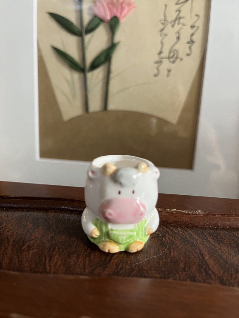 Cow Ceramic Holder (Category: Pots & Planters) located in Taguig. Submitted by minmin_parker (Listing ID 1458759835, Image 1). Description: - Adorable ceramic cow planter - Features green overalls - Ideal for small succulents or air plants - Adds a whimsical touch to desks and shelves - Makes a great gift for plant lovers or decor enthusiasts - Approximately 3 inches tall.