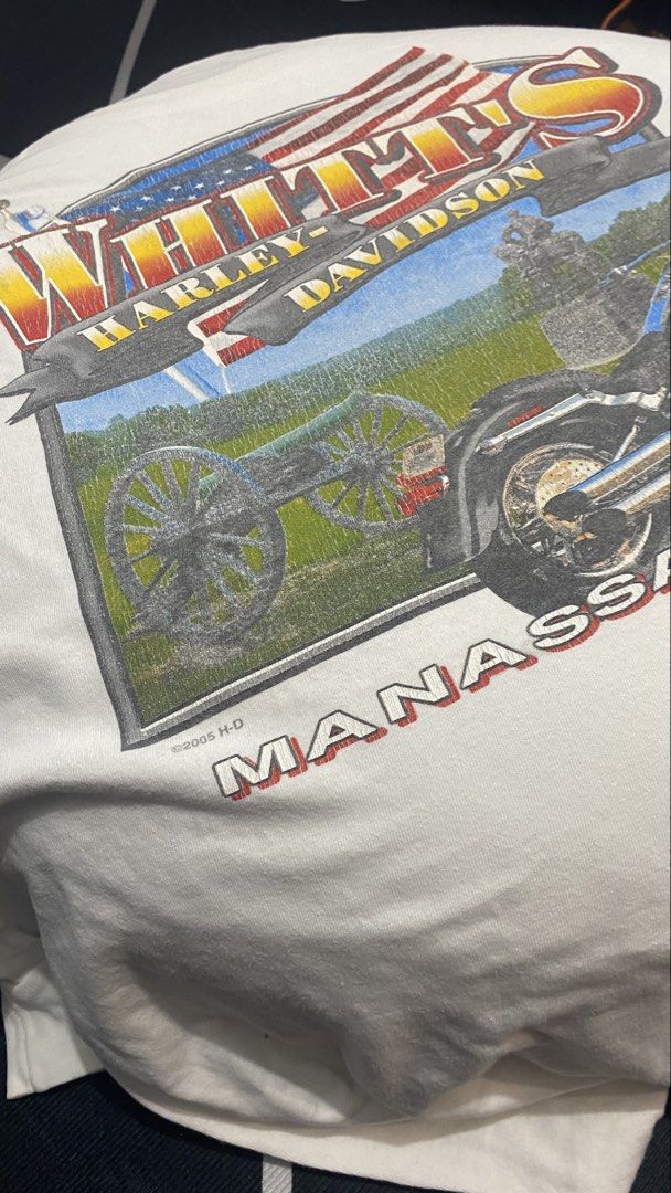 Harley-Davidson T-Shirt Manassas VA Eagle Skull Piston (Category: Tshirts & Polo Shirts ) located in Porac. Submitted by moethrifter (Listing ID 1458792315, Image 2). Description: - White Harley-Davidson T-shirt - Size: XL - Front Graphic: American flag, motorcycle, cannon, 'Whitts Harley-Davidson Manassas, VA' - Back Graphic: Large eagle with skull, piston, and flames - Design: Detailed and colorful.
