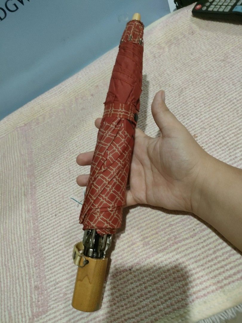 Hogan U.S.A. Red Patterned Folding Umbrella (Category: Umbrellas) located in Bulacan. Submitted by hunterherojapanjdm (Listing ID 1458834327, Image 1). Description: - Red folding umbrella with a stylish geometric pattern. - Features a classic wooden handle with the Hogan U.S.A. logo. - Compact and portable design, perfect for on-the-go. - Secure snap closure strap for easy fastening. - Effortlessly fits into your bag for convenient storage..