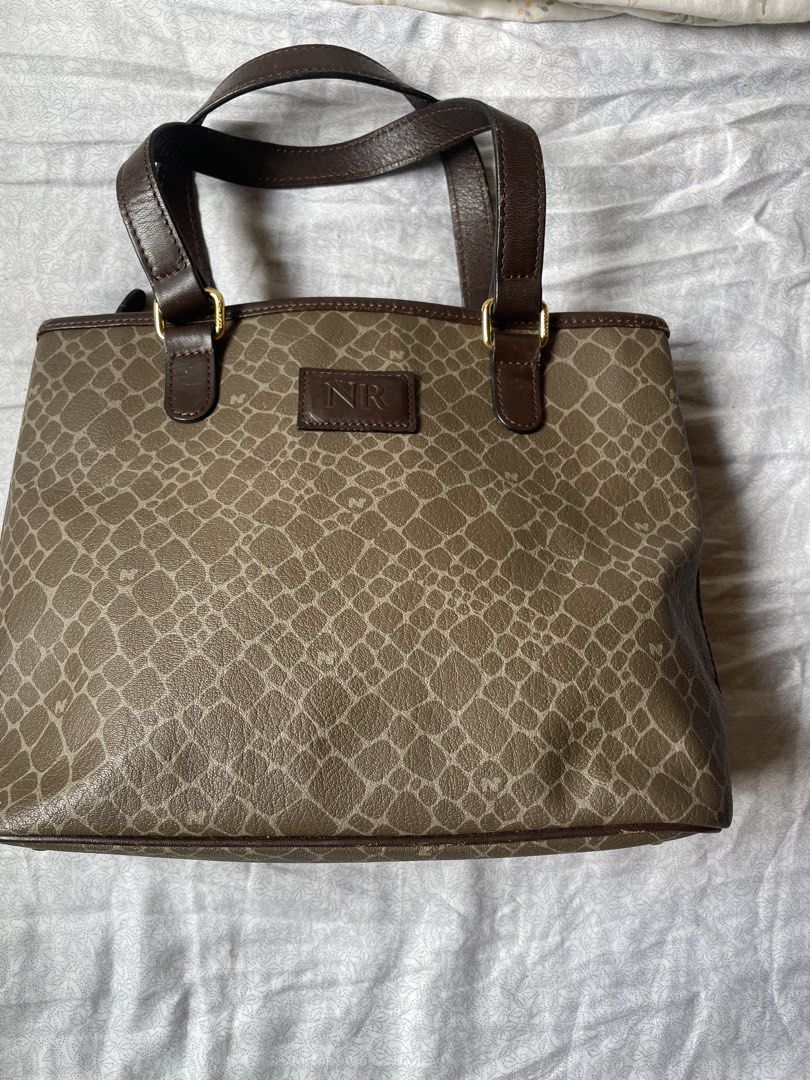 Nina Ricci NR Monogram Tote Bag (Category: Luxury Bags & Wallets) located in Cavite. Submitted by msandysgoodies (Listing ID 1458714632, Image 1). Description: - Classic Nina Ricci tote bag - Signature NR monogram pattern all over - Dark brown leather trim and handles - Gold hardware details - Zipper closure on back pocket - Four metal studs on the bottom for protection - Stylish and practical for everyday use.