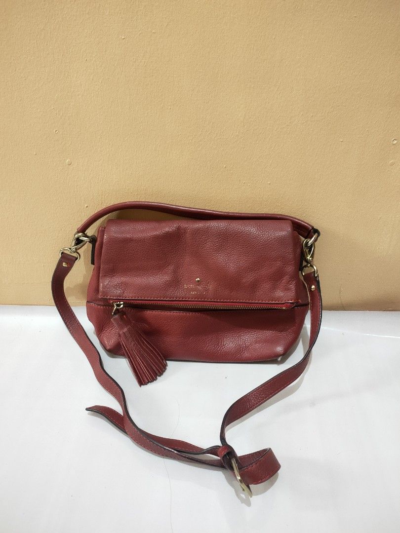 Og Kate Spade (Category: Cross-body Bags) located in Urdaneta. Submitted by assortedprelovedd (Listing ID 1458778352, Image 1). Description: - Genuine red leather Kate Spade crossbody bag - Features a stylish tassel detail on the front zipper - Adjustable strap for a customized, comfortable fit - Elegant gold hardware accents - Versatile: Ideal for everyday errands or a glamorous night out.