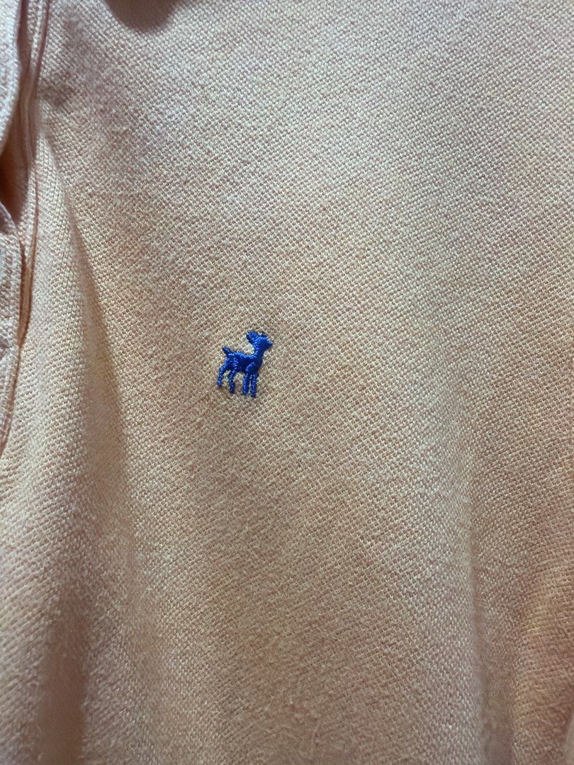 Old Navy Orange Polo Shirt Size M (Category: Shirts) located in Muntinlupa City. Submitted by lybns (Listing ID 1458810552, Image 2). Description: - Orange polo shirt from Old Navy - Size: Medium (M) - Features a small blue embroidered deer logo on the chest - Classic two-button placket - Made in Cambodia - Ideal for casual wear.