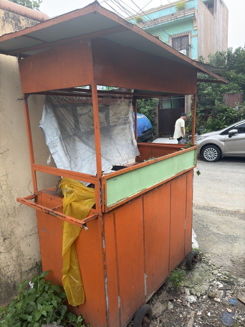 Orange Food Cart with Wheels (Category: Food Organization & Storage) located in Quezon City. Submitted by nathanielstore (Listing ID 1458773875, Image 1). Description: - Orange food cart with green trim - Equipped with wheels for easy mobility - Sturdy metal frame with a roof - Includes attached plastic sheeting - Ideal for starting a small business or street food vending - Ready for your custom setup.