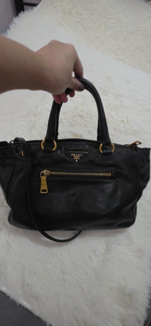 Prada Black Leather Top Handle Bag (Category: Luxury Bags & Wallets) located in Pasig City. Submitted by lfboutique (Listing ID 1458779983, Image 1). Description: pasig loc no cod no damage, professionally recolored minor fade on hardware pls see photos for reference - Authentic black leather Prada handbag - Elegant gold hardware details - Versatile top handle and detachable shoulder strap - Protective studs on the bottom - Shows some signs of we