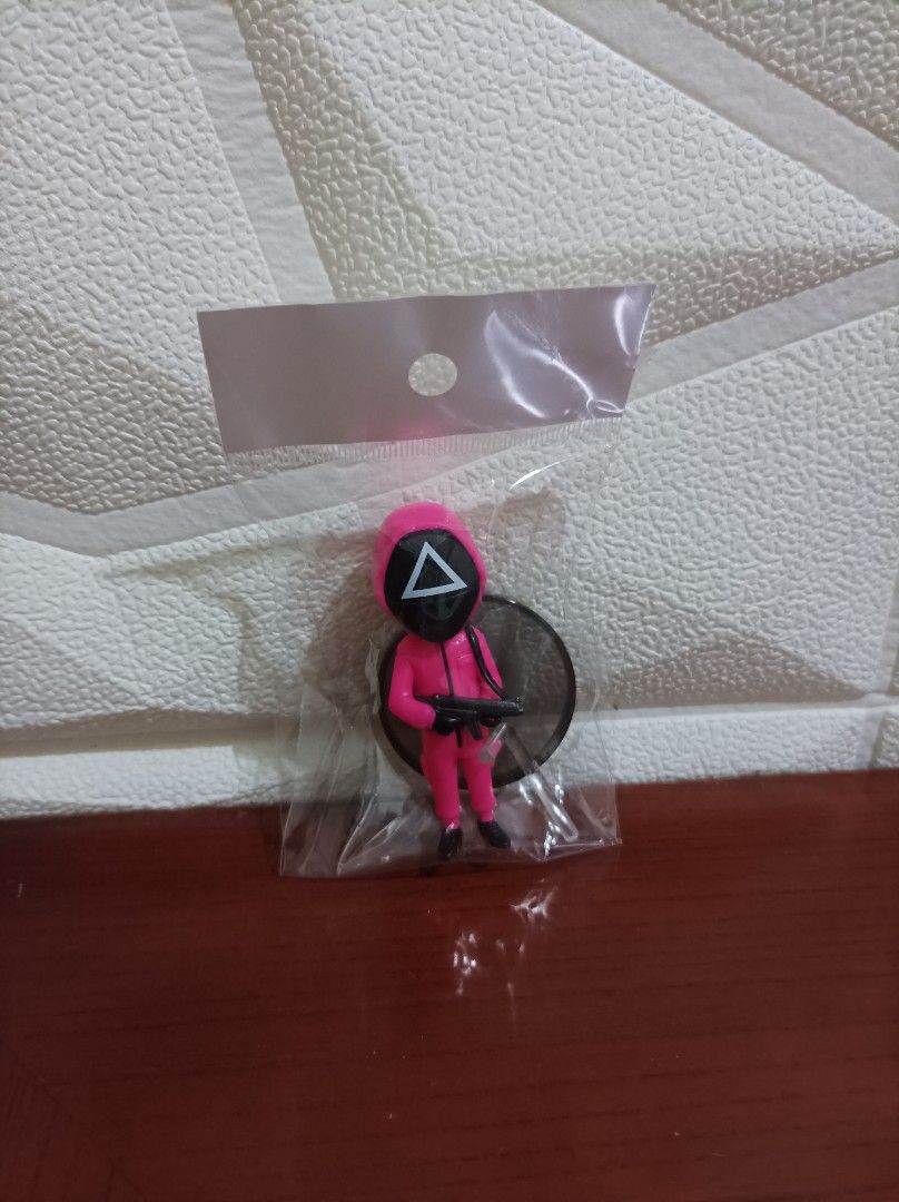 Squid Game Soldier Figure with Gun (Category: Figurines & Statues) located in Bacoor. Submitted by kuroochiii94695 (Listing ID 1458725358, Image 1). Description: - Pink Squid Game Soldier Figure - Features iconic triangle symbol on mask - Comes with a gun accessory - Includes a black circular display base - Brand new, still in original packaging - Ideal collectible for Squid Game enthusiasts.