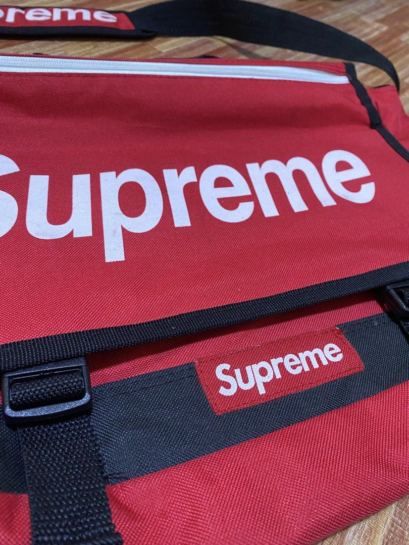 Supreme Red Messenger Bag (Category: Luxury Bags & Wallets) located in Manila. Submitted by drip-from-thrift (Listing ID 1458711954, Image 2). Description: - Classic red Supreme messenger bag - Features iconic Supreme logo on front and strap - Made from durable material for everyday use - Adjustable strap for comfortable wear - Zipped main compartment for secure storage - Essential item for any Supreme enthusiast.