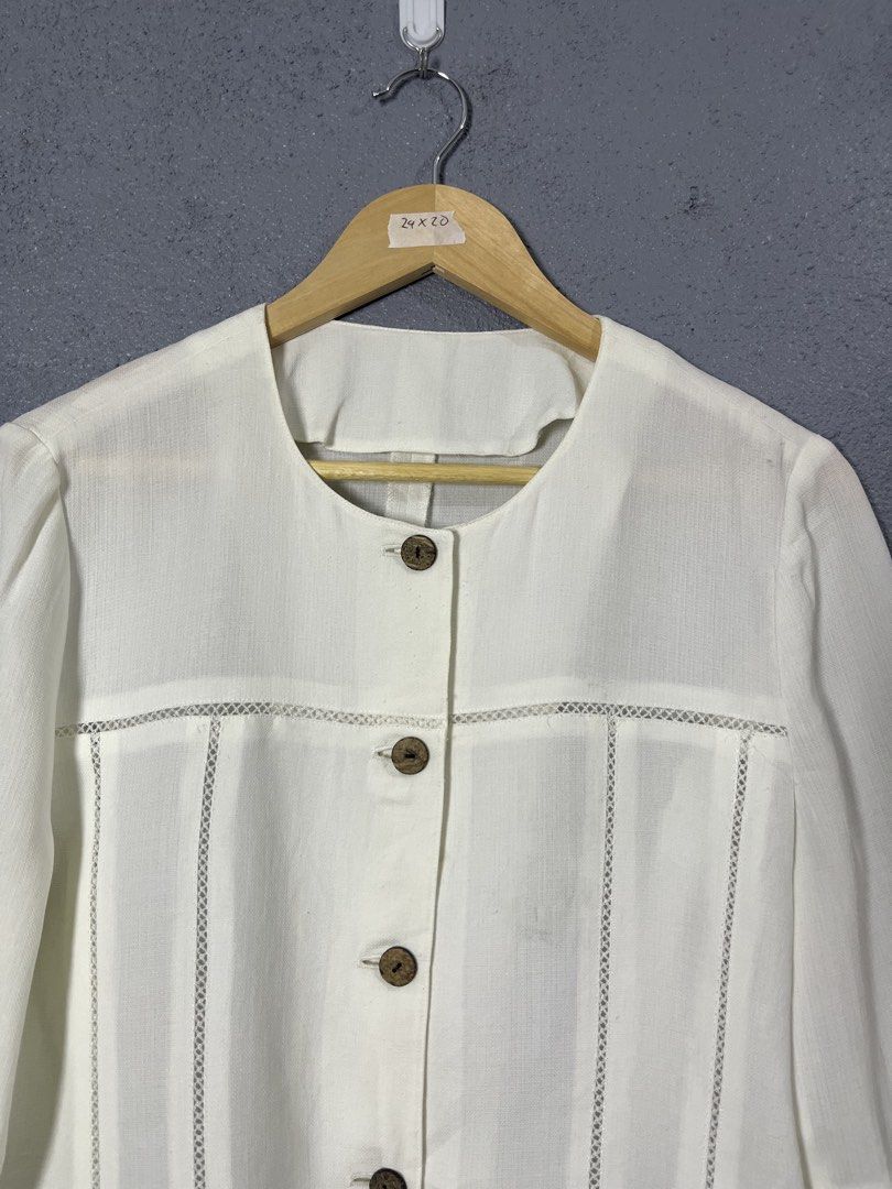 The Pink Tea White Button-Up Blouse (Category: Blouses) located in Famy. Submitted by basicthrifted (Listing ID 1458727477, Image 2). Description: - Brand: The Pink Tea - Color: White - Sleeve Length: Three-quarter sleeves with cuff - Neckline: Simple round neckline - Closure: Wooden-style buttons - Details: Unique textured details on chest and shoulders - Style: Versatile for casual or smart-casual outfits.