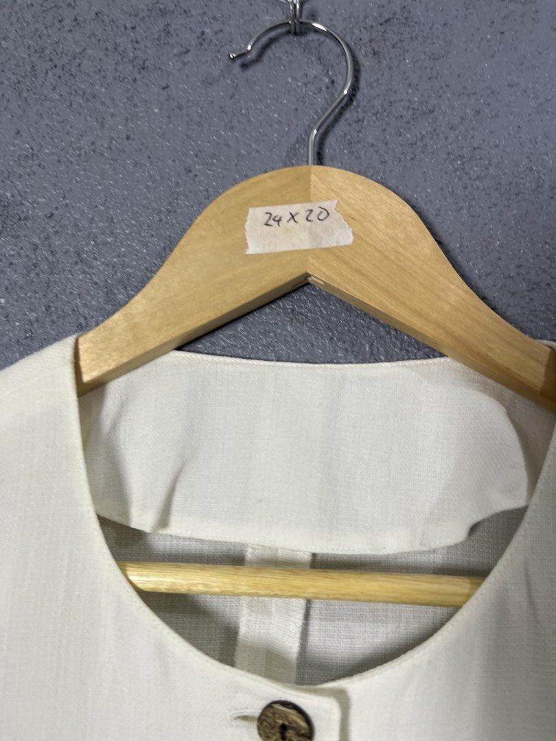 The Pink Tea White Button-Up Blouse (Category: Blouses) located in Famy. Submitted by basicthrifted (Listing ID 1458727477, Image 3). Description: - Brand: The Pink Tea - Color: White - Sleeve Length: Three-quarter sleeves with cuff - Neckline: Simple round neckline - Closure: Wooden-style buttons - Details: Unique textured details on chest and shoulders - Style: Versatile for casual or smart-casual outfits.