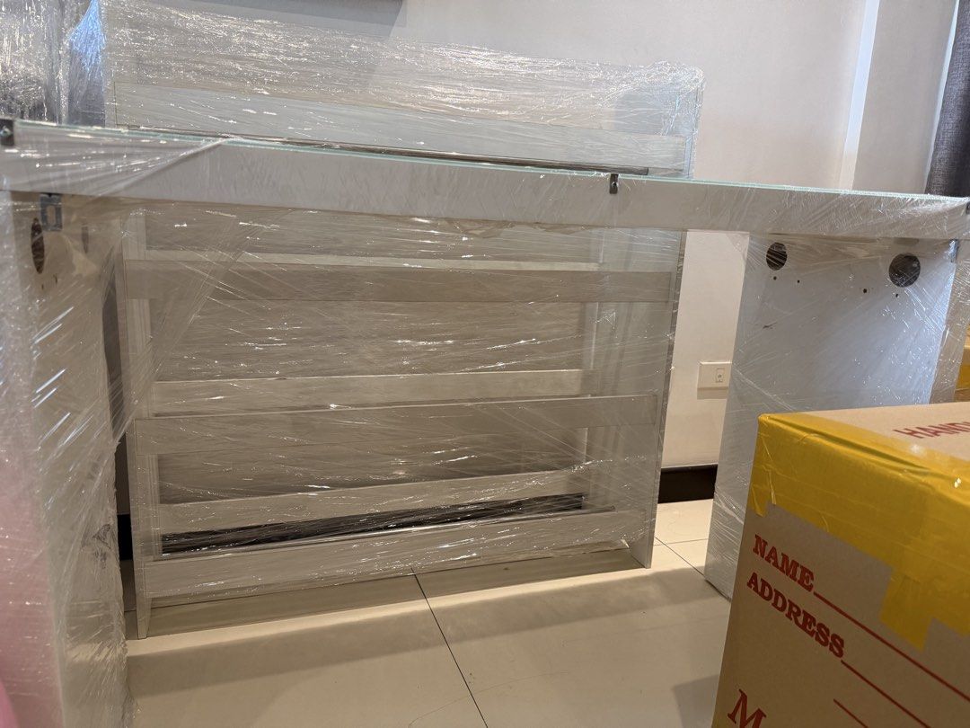 White Modern Desk with Glass Top (Category: Tables & Sets) located in Mandaluyong City. Submitted by mamaseller1829 (Listing ID 1458728528, Image 2). Description: - Sleek white desk with a smooth glass top - Integrated shelves underneath for convenient storage - Clean and minimalist design, ideal for study or work spaces - Simple assembly process - Selling because of an upcoming move SIRA NA DRAWER PART.