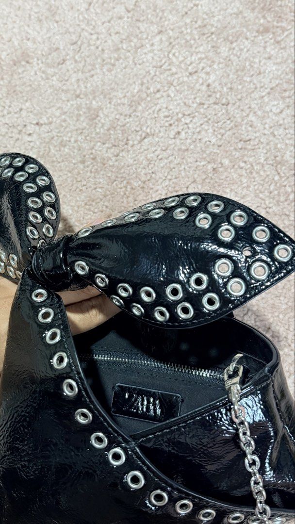 Zara Black Patent Bow Bag with Studs (Category: Luxury Bags & Wallets) located in Calauan. Submitted by lovefelice (Listing ID 1458775305, Image 3). Description: - Zara black patent handbag - Features a cute bow detail with silver studs - Comes with a silver chain strap - Interior zippered pocket - Ideal for night outs or adding an edgy touch to your outfit.
