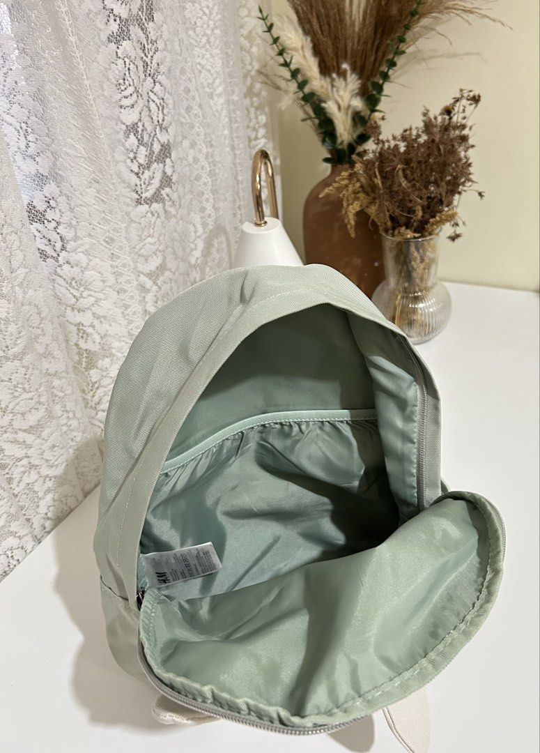 Authentic H&M Bunny Backpack (Category: Babies & Kids Fashion) located in Manila. Submitted by maison_marie (Listing ID 1453772510, Image 2). Description: Sage green backpack with front zip pocket for easy-access essentials. Side mesh pocket for a water bottle. Adjustable shoulder straps. Lightweight and perfect for toddlers or young kids. Condition: There is slight fading on the pink cheek details. Other than that, the bag is in good pre-loved c