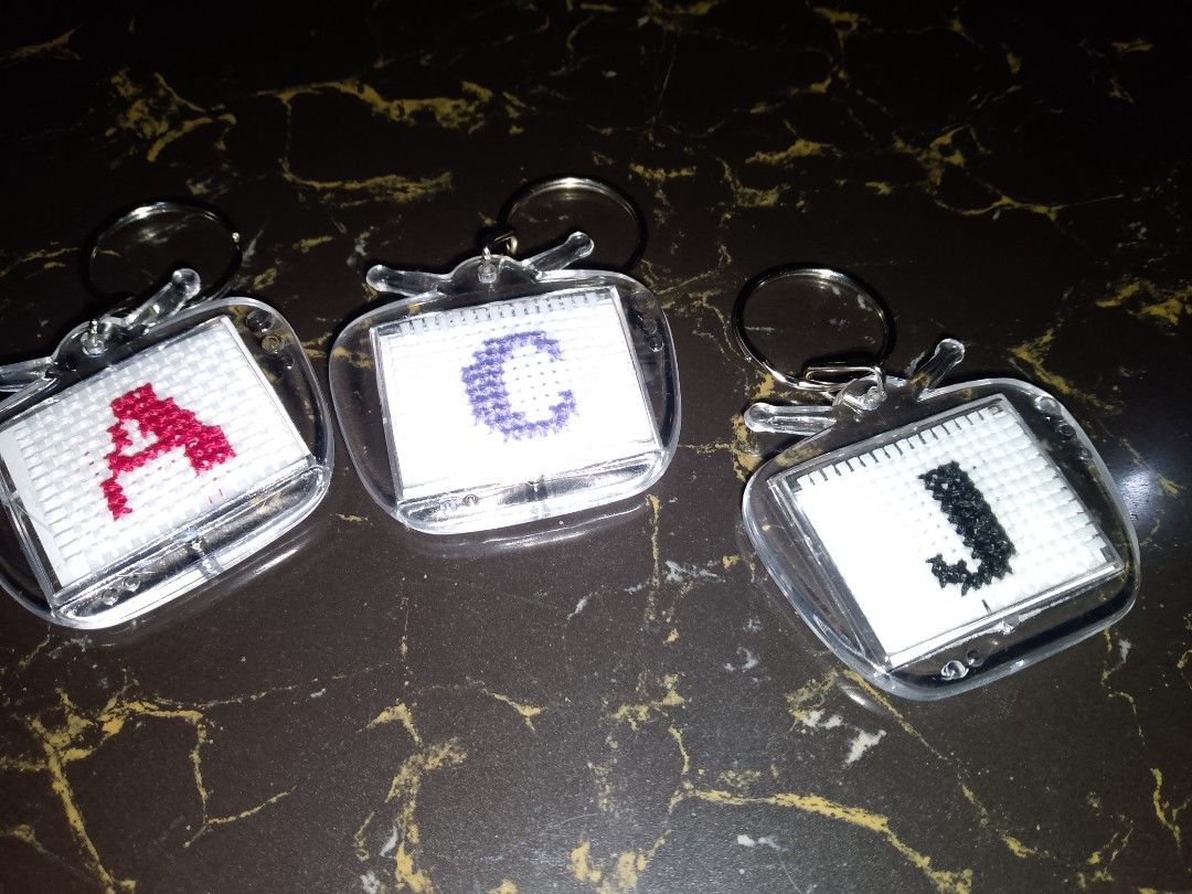 Custom Letter Cross-Stitch Keychains - A, C, J (Category: Handmade Craft) located in Manila. Submitted by perapern (Listing ID 1453638703, Image 1). Description: - Handmade cross-stitch keychains - Unique TV-shaped casing - Available letters: A (red), C (purple), J (black) - Ideal for personalizing bags and keys - Great as a unique gift idea - Sold as a set.