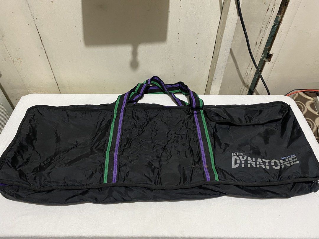 KBC Dynatone HS-000 Keyboard Gig Bag (Category: Musical Instruments) located in Manila. Submitted by resi.diaz (Listing ID 1453780287, Image 1). Description: - Approx: 103 x 35 x 11 cm - Black gig bag designed for keyboards. - Features stylish purple and green stripe accents on handles and trim. - Prominently displays the KBC Dynatone HS-000 logo on the front. - Offers ample interior space to comfortably fit your keyboard. - Secure zip closure en