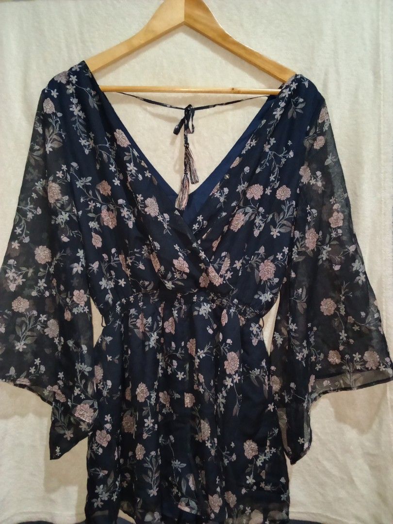 Navy Floral Bell Sleeve Romper with Tie Back (Category: Rompers) located in Manila. Submitted by sionnygaer36822 (Listing ID 1453653268, Image 1). Description: - Navy blue romper with a charming floral print. - Features stylish flowy bell sleeves. - Flattering V-neckline. - Adjustable tie detail at the back for a customized fit. - Comfortable elasticated waist. - Versatile for casual days or nights out with friends..