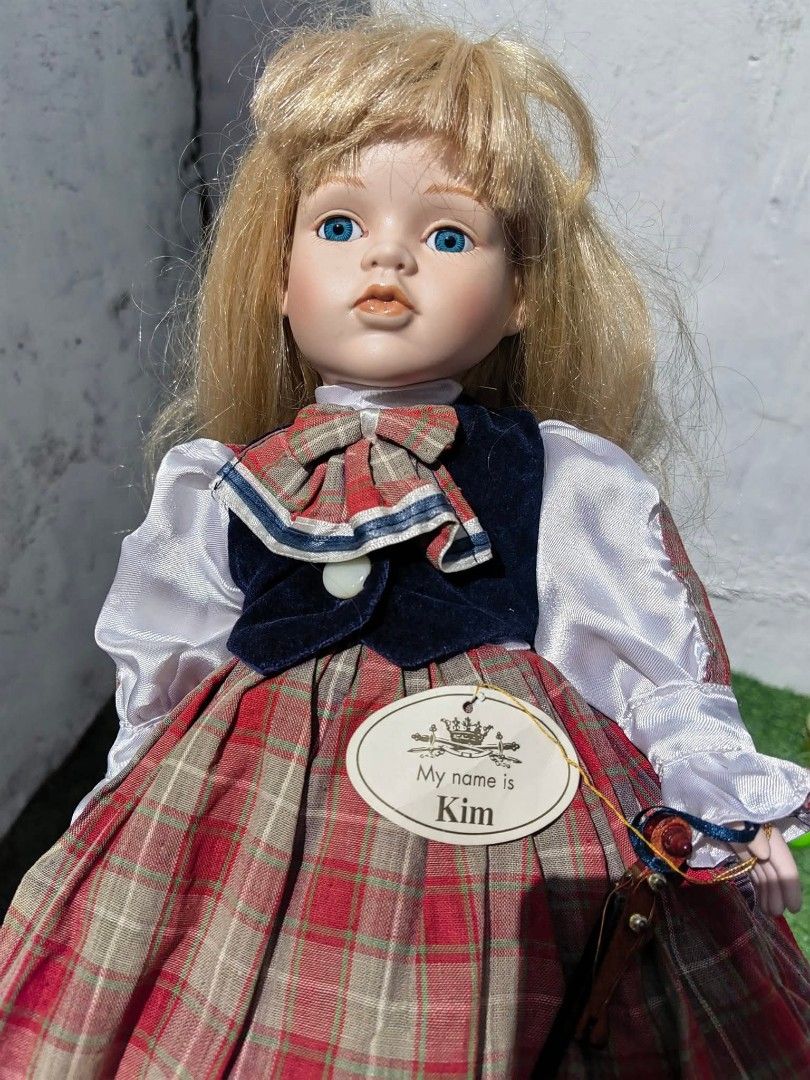 Porcelain Doll (Category: Figurines & Statues) located in Cebu City. Submitted by dudes_villanueva (Listing ID 1453672791, Image 2). Description: Porcelain Doll Brand: Leonardo Collector's 📌 The doll has fine porcelain bisque skin, painted facial accents, glass-like blue eyes, synthetic blonde hair with bangs, and bare feet. 📌 She is styled in a traditional Victorian- or European-inspired outfit, featuring a red and beige tartan plaid pinafore 