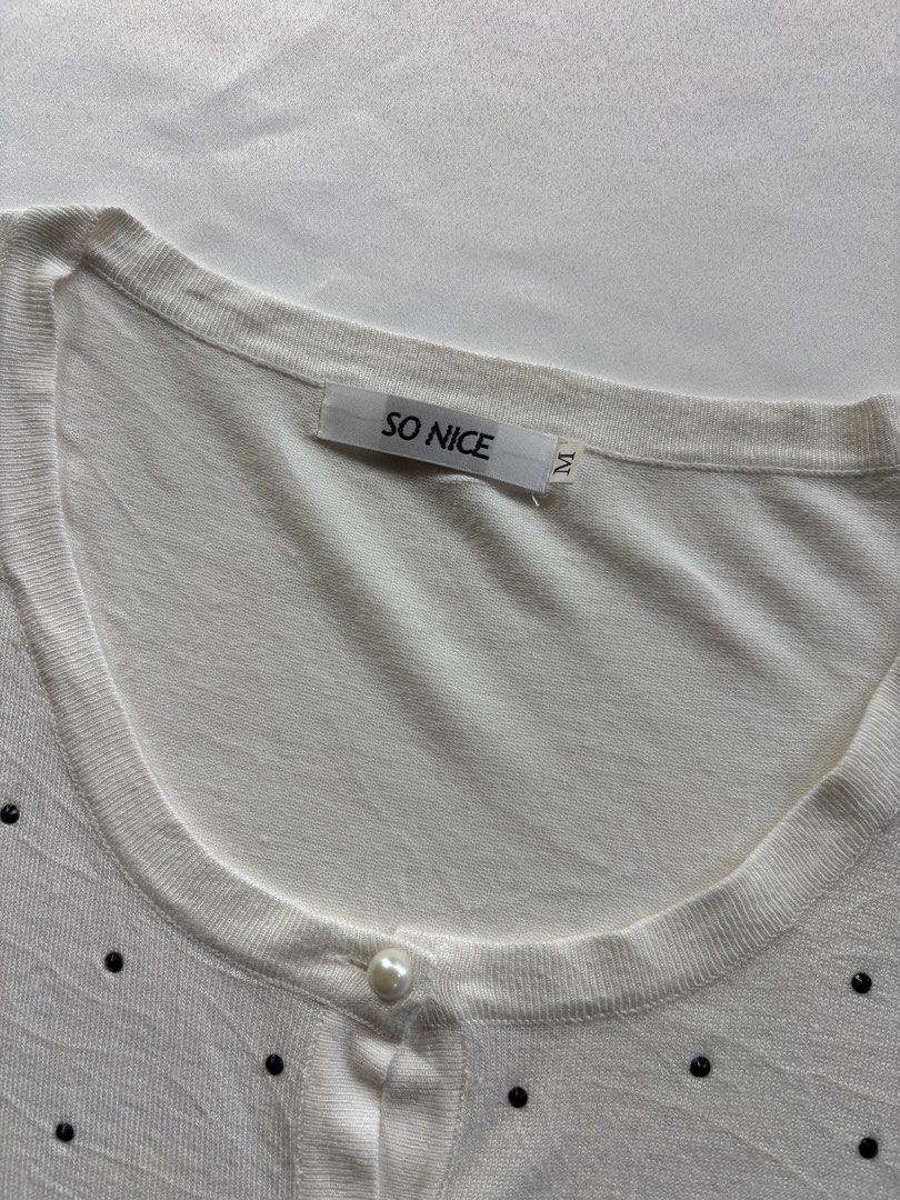 SO NICE White Embellished Button Up Cardigan Size M (Category: Coats, Jackets and Outerwear) located in Iloilo. Submitted by iconicangie (Listing ID 1453788037, Image 3). Description: - Brand: SO NICE - Color: White - Size: M - Neckline: Round - Closure: Button-up front with pearl-like buttons - Embellishments: Scattered black details all over - Sleeves: Three-quarter length with slight shoulder puff - Hem & Cuffs: Ribbed.