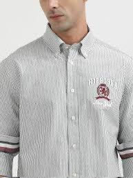 Tommy Hilfiger Striped Button-Down Shirt with Crest Logo (Category: Tshirts & Polo Shirts ) located in Kidapawan. Submitted by azythrift (Listing ID 1453648970, Image 1). Description: - Classic Tommy Hilfiger button-down shirt - Features thin grey and white stripes - Embroidered Tommy Hilfiger crest logo on chest - Striped detail on cuffs - Sharp, clean look - Ideal for casual or smart-casual occasions.